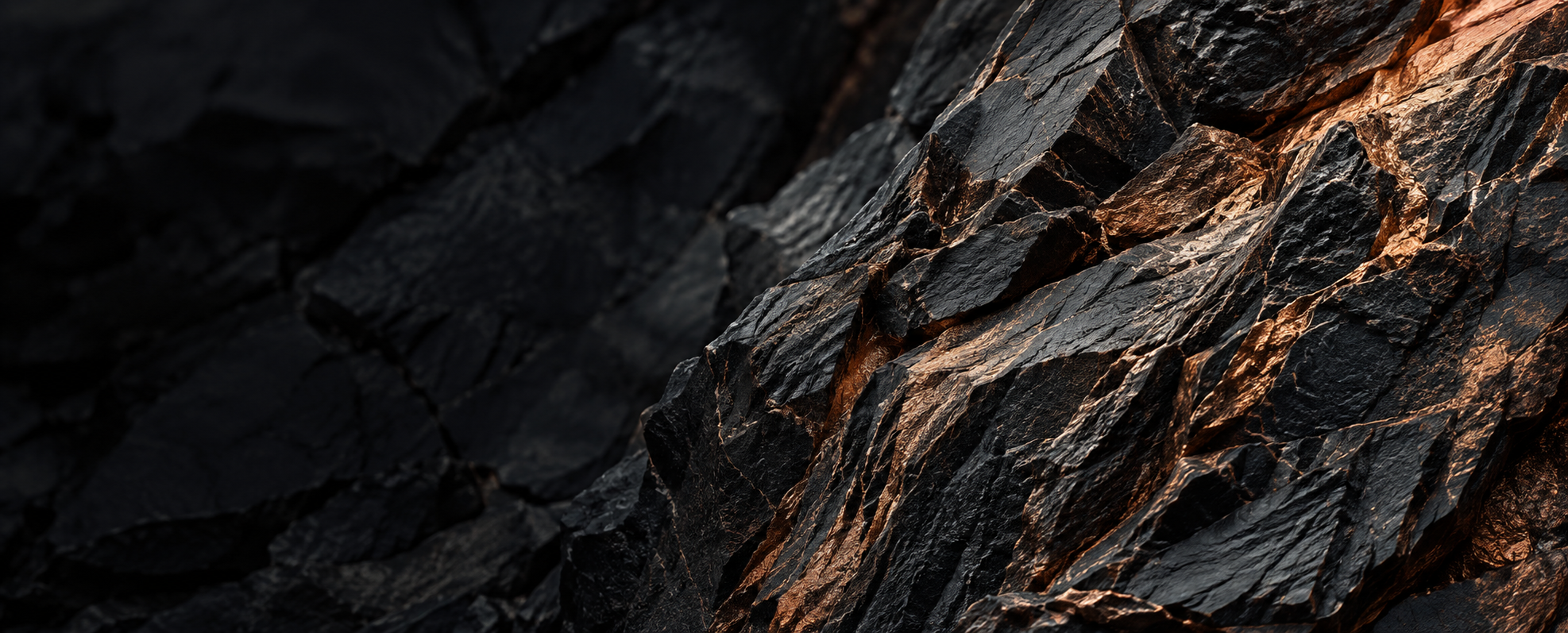 Illustrative close-up of dark mineral rock with warm copper light